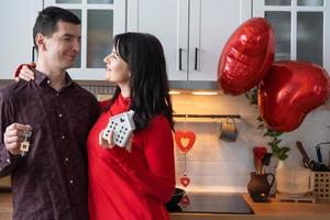 Man and woman in love date at home in kitchen with keys of house. Valentine's Day, happy couple, love story. Love nest, mortgage, relocation, purchase, real estate, housing for young family photo