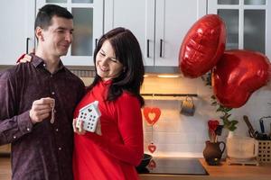 Man and woman in love date at home in kitchen with keys of house. Valentine's Day, happy couple, love story. Love nest, mortgage, relocation, purchase, real estate, housing for young family photo