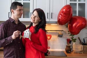 Man and woman in love date at home in kitchen with keys of house. Valentine's Day, happy couple, love story. Love nest, mortgage, relocation, purchase, real estate, housing for young family photo