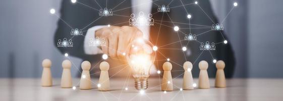 thinking and creative, Businessman hand holding light bulb on the wooden people, Teamwork and idea concept, Successful team leader, Businessman hand choose people standing out from the crowd. photo