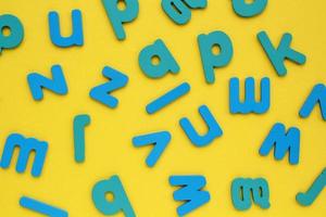 Pile of jumbled messy letters pattern on yellow background. Latin alphabet block colored letters. Dyslexia awareness confusion brain thinking psychology problem. English learning concept. Close up photo