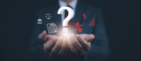 Tax with Ask question online concept, Businessman hold interface question marks tax payment optimization business finance, Concept of searching for an answer, Uncertainty, and problem-solving. photo
