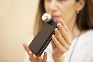 A dermatologist doctor shows a modern device using light, a phone application and a camera to examine birthmarks and moles. photo