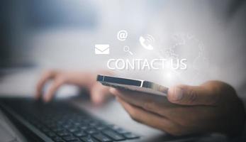 comunicación y contáctenos o la gente de la línea directa de atención al cliente se conecta. mano usando una computadora portátil y tocando los íconos de contacto de la pantalla virtual, correo electrónico y dirección, chat en vivo con wifi de Internet. foto