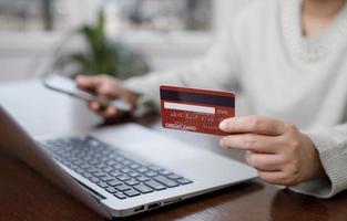 Woman holding credit card for makes a purchase on the Internet on the laptop computer with credit card, online payment, shopping online, e-commerce, internet banking, spending money concept. photo