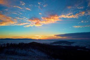 Sunset over mountains covered with forest photo