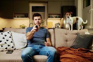 man use remote control to watch tv photo