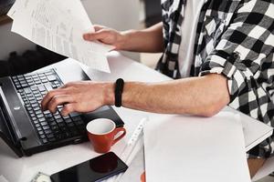 Man works at home office with laptop and documents photo