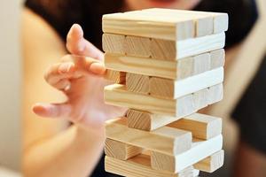 Family play board game. Hands take wooden block from tower. photo