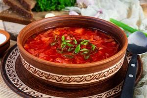 borscht ucraniano tradicional con cebolla verde y crema agria. deliciosa sopa de remolacha en un tazón con pan de centeno foto