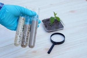 Closeup hand wears blue glove hold test tubes that contain sample soil. Concept, soil quality inspection, research and science experiment. Laboratory. Find the best from different soil type and source photo