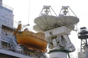 Radar antenna and lifeboat are located ship. photo