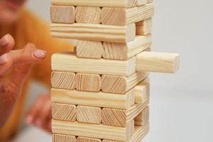 Family play board game. Hands take wooden block from tower. photo
