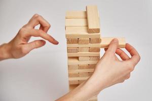 Family play board game. Hands take wooden block from tower. photo