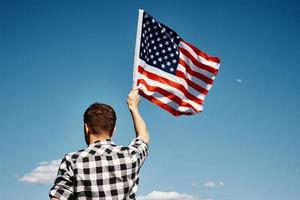 Man holds usa national flag against blue sky photo