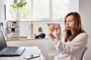 mujer juega con papel normal en la oficina en casa. procrastinar en el trabajo remoto foto
