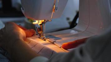 processus de couture sur une machine à coudre, une aiguille avec un fil et un support gros plan sur le tissu à carreaux blanc. video