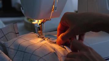 processo de costura em uma máquina de costura, uma agulha com um fio e um close-up do suporte costuram o tecido xadrez branco. video