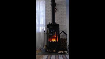Black stove, fireplace in interior of house in loft style. Alternative eco-friendly heating, warm cozy room at home, burning wood. vertical video