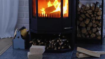 Fuel briquettes made of pressed sawdust for kindling the furnace - economical alternative eco-friendly fuel for the fireplace in the house. Firewood is burning in the oven in the interior video