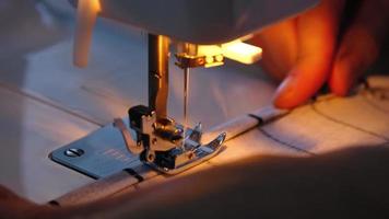 Sewing process on a sewing machine, a needle with a thread and a holder close-up stitch the white checkered fabric. video