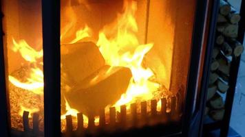 Fuel briquettes made of pressed sawdust for kindling the furnace - economical alternative eco-friendly fuel for the fireplace in the house. Firewood is burning in the oven in the interior video