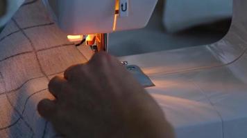 processus de couture sur une machine à coudre, une aiguille avec un fil et un support gros plan sur le tissu à carreaux blanc. video