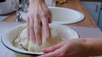Hands knead thick dough on the kitchen table. Baking at home, aroma and comfort. Close-up video