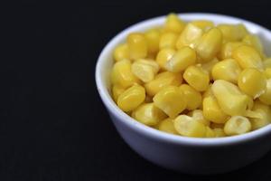 Fresh canned corn. Corn kernels in a white salad bowl. Corn in a cup. photo