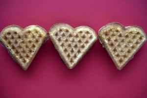 corazones de gofres sobre un fondo rojo. Día de San Valentín. productos de confitería en forma de corazón. foto