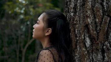 Bogenschützin lehnt und ruht auf einem braunen Baum im Dschungel video