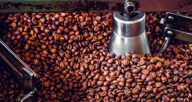 Freshly roasted aromatic coffee beans over a modern coffee roasting machine. photo