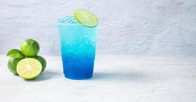 Blue Hawaiian drink in a plastic glass and lime on white background photo