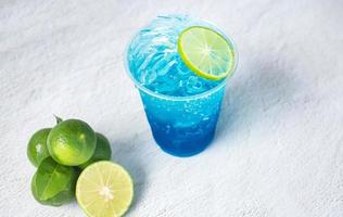 Blue Hawaiian drink in a plastic glass and lime on white background photo