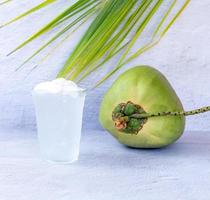 bebida de agua de coco helada en un vaso de plástico y coco sobre fondo blanco foto