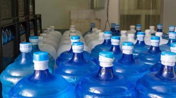 The blue water gallon and white gallon containing drinking water have been sealed with a plastic seal in the drinking water plant to wait for delivery photo