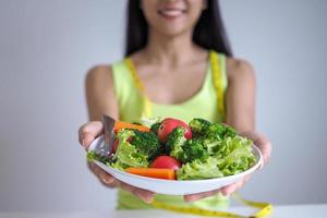 las mujeres hermosas asiáticas están felices de comer ensalada de verduras. foto