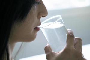 una hermosa mujer asiática está feliz de beber agua. para una buena salud y piel foto