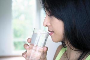 A beautiful Asian woman is happy to drink water. For good health and skin photo