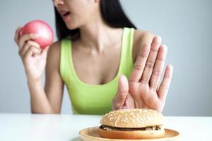 las mujeres asiáticas empujan el plato de hamburguesas y eligen comer manzanas para una buena salud. foto