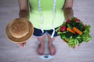 mujer pesando y sosteniendo un plato de verduras con hamburguesa. concepto de comida foto