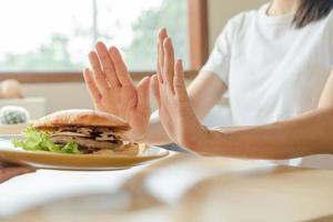 belleza cuerpo femenino delgado confundir hamburguesa. mujer en restaurante logra el objetivo de pérdida de peso para una vida saludable, loca por la delgadez, cintura delgada, nutricionista. dieta, forma del cuerpo. foto