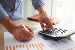 Men business men are calculating their income. Use the calculator and view the data graph. Analytical thinking concept photo