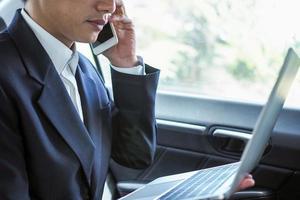 Business people talk on the phone and search for information on a laptop while traveling to negotiate off-site business. photo