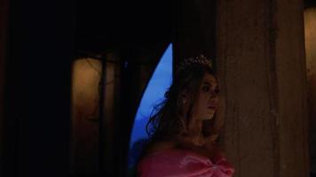 eine Prinzessin mit einem rosa Kleid, die langsam im Dunkeln läuft, während sie eine Krone und eine Tiara trägt