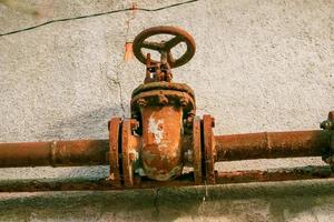 Rusty old gas tap on the background of the wall of the house. photo