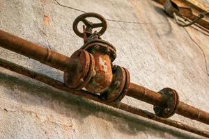 Rusty old gas tap on the background of the wall of the house. photo