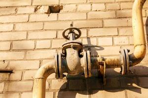 Rusty old gas tap on the background of the wall of the house. photo