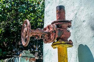 Rusty old gas tap on the background of the wall of the house. photo