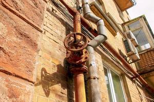 Rusty old gas tap on the background of the wall of the house. photo